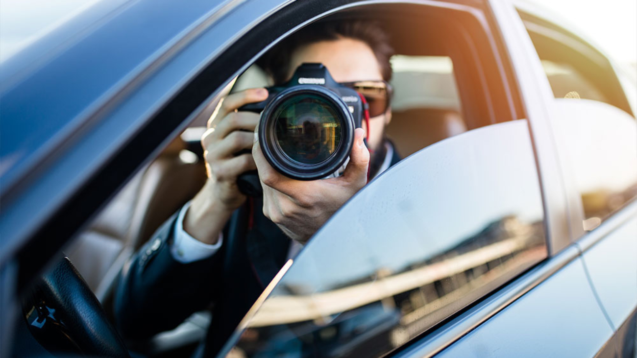 Detective con una cámara de fotos dentro del coche