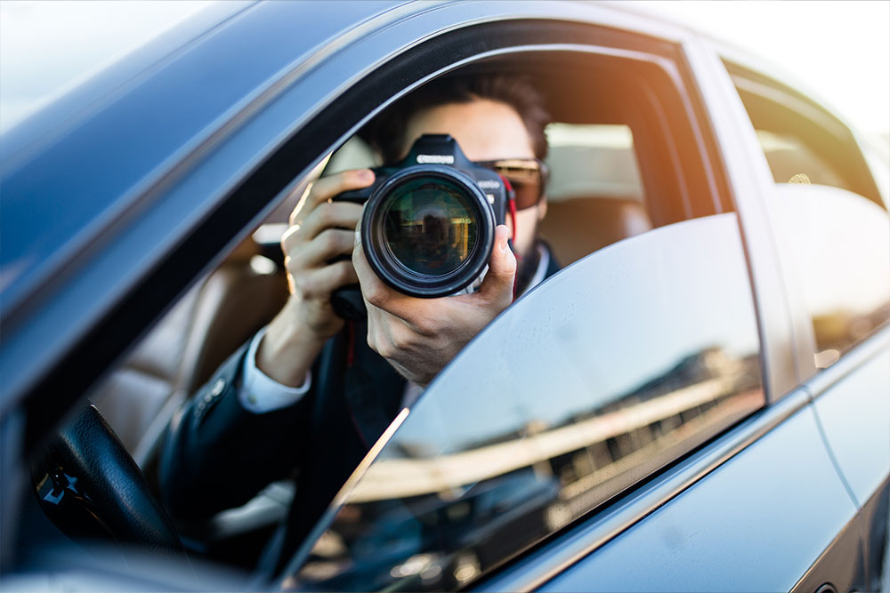 Detective con una cámara de fotos dentro del coche